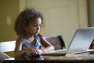 Mixed race girls using laptop at table