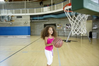 Mixed race girl playing basketball on court