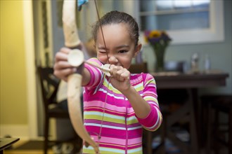 Mixed race girl playing with bow and arrow