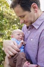 Father holding newborn son outdoors