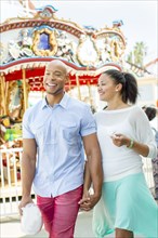 Mixed race couple holding hands at amusement park