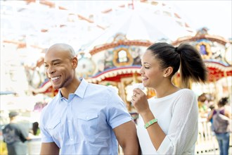Mixed race couple laughing at amusement park