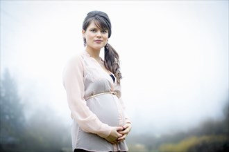 Caucasian woman holding pregnant belly outdoors