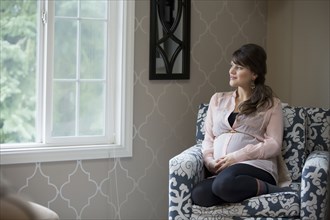 Pregnant Caucasian woman sitting in living room