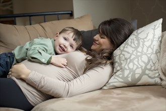 Pregnant Caucasian woman laying with son