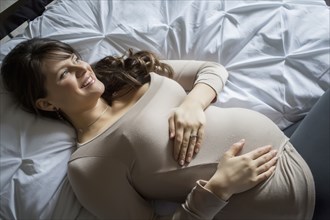 Pregnant Caucasian woman laying on bed