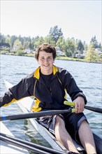Mixed race teenage boy rowing scull on lake