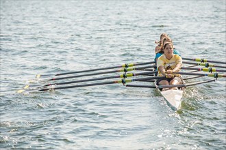 Teenagers rowing together on lake