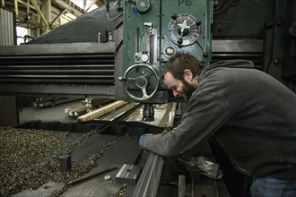 Caucasian man working at machinery in metal shop