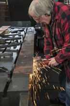 Caucasian man sanding metal in metal shop