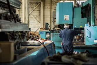 Caucasian man using machinery in metal shop