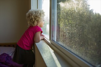 Mixed race girl looking out window
