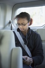 Mixed race girl using digital tablet in back seat of car