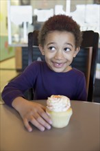 Mixed race girl having cupcake in bakery