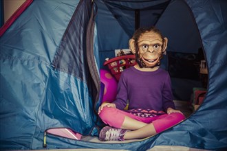 Mixed race girl wearing mask in tent