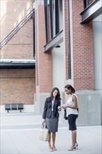 Businesswomen talking on city sidewalk