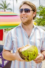 Caucasian man drinking from coconut on beach