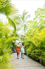 Lesbian couple holding hands on tropical walkway