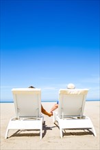 Couple holding hands in lounge chairs on beach