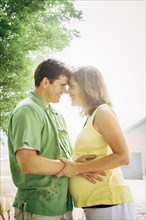 Man hugging pregnant wife outdoors