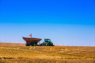 Tractor driving in crop field in rural landscape