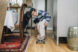 Mixed race boy riding skateboard in kitchen