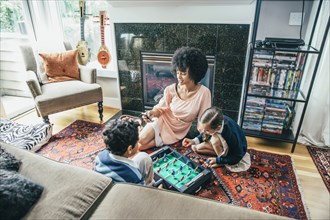 Mixed race family playing foosball on living room floor