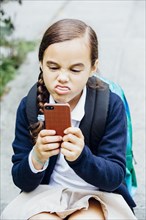 Mixed race girl making a face at cell phone