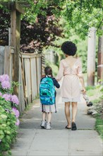 Mixed race mother and daughter walking on suburban sidewalk