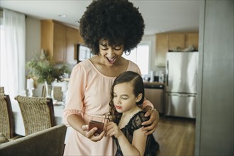 Mixed race mother and daughter using cell phone