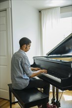 Mixed race boy playing piano