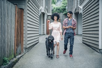 Mixed race mother and son walking dog in suburban apartment complex