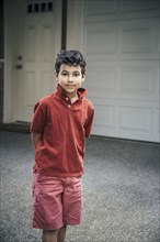 Mixed race boy standing on driveway