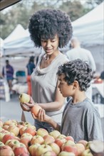 Mixed race boy shopping with mother at farmers market