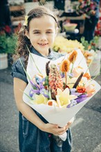 Mixed race girl holding bouquet of flowers outdoors