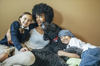 Mixed race mother and children hugging dog
