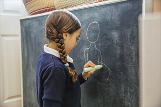 Mixed race girl drawing on chalkboard