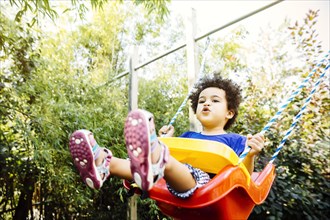 Low angle view of mixed race girl playing on swing