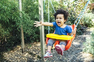 Low angle view of mixed race girl shouting on swing
