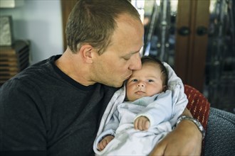 Caucasian father kissing baby boy in living room