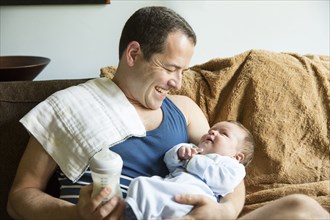 Caucasian father holding baby boy in living room