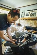 Caucasian father fastening baby boy in car seat