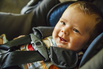Caucasian baby boy smiling in car seat