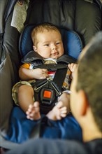 Caucasian father admiring baby boy in car seat