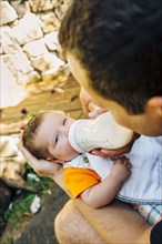 Caucasian father feeding baby boy outdoors
