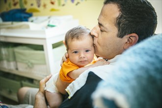 Caucasian father kissing baby boy in nursery