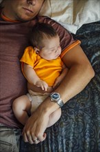 Caucasian father and baby boy sleeping on bed