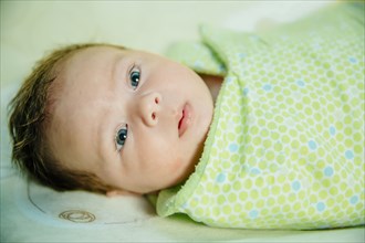 Caucasian baby boy swaddled in blanket