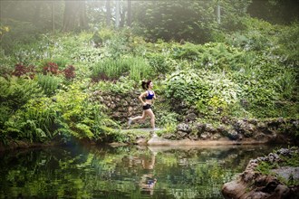 Caucasian woman running near lake in park