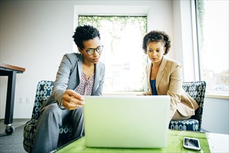 Businesswomen using laptop in office lobby